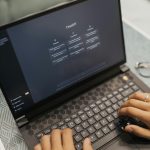 Close-up of hands typing on a laptop with AI software on the screen, highlighting modern technology use.