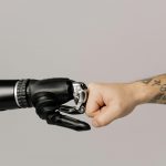 Close-up of a human fist bumping a prosthetic hand, symbolizing technology and human connection.